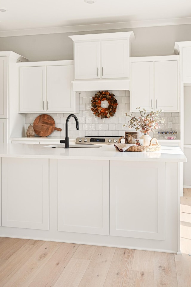 kitchen with sink, white cabinets, and light wood-type flooring