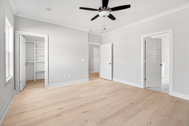 unfurnished bedroom featuring light hardwood / wood-style flooring, a spacious closet, ceiling fan, crown molding, and a closet