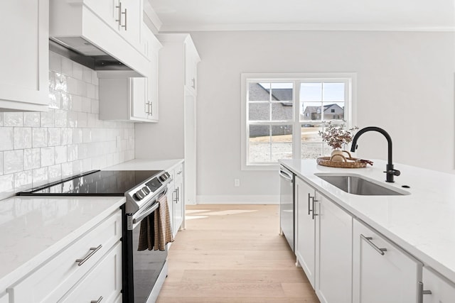 kitchen featuring appliances with stainless steel finishes, white cabinetry, sink, ornamental molding, and light stone counters