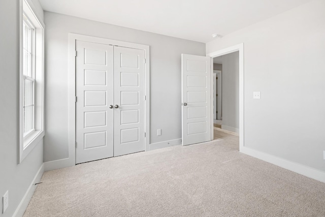 unfurnished bedroom with light colored carpet and a closet