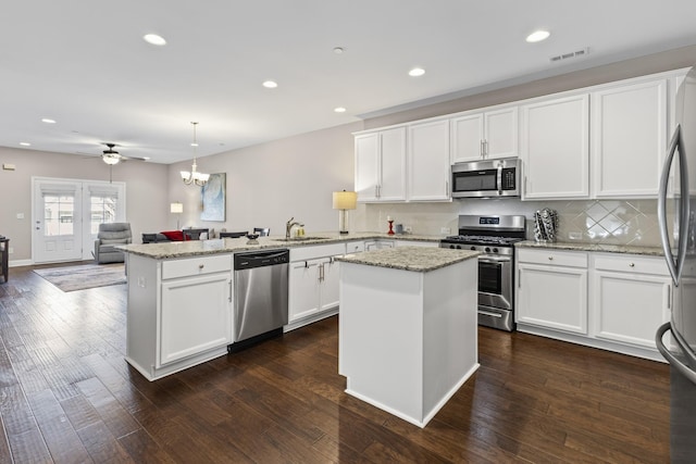 kitchen with appliances with stainless steel finishes, pendant lighting, sink, a center island, and kitchen peninsula