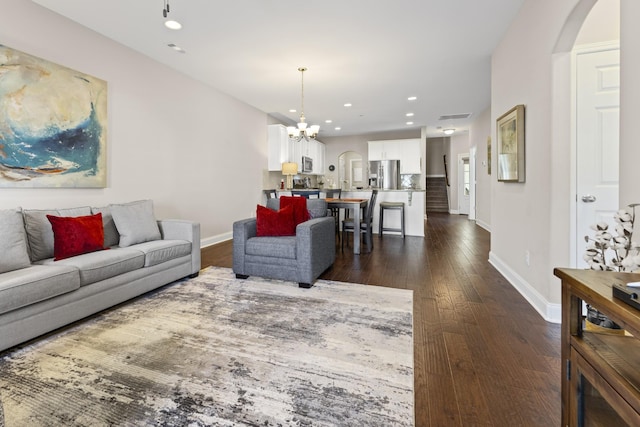 living room featuring a notable chandelier and dark wood-type flooring