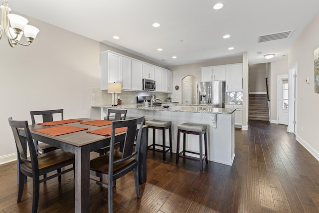 dining area with dark hardwood / wood-style floors and an inviting chandelier