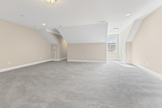 additional living space featuring light carpet and vaulted ceiling