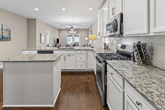 kitchen featuring stainless steel appliances, dark hardwood / wood-style floors, a center island, white cabinets, and kitchen peninsula