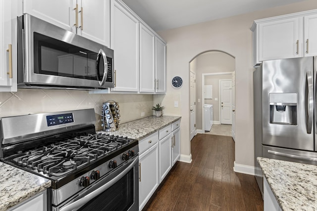 kitchen with white cabinetry, light stone counters, appliances with stainless steel finishes, dark hardwood / wood-style flooring, and backsplash