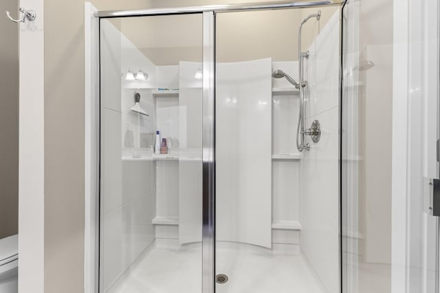 bathroom featuring toilet and a shower with shower door