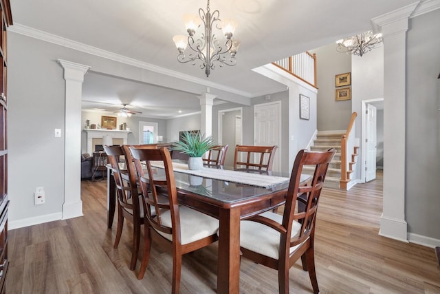 dining room with light hardwood / wood-style floors, ceiling fan with notable chandelier, ornamental molding, and decorative columns