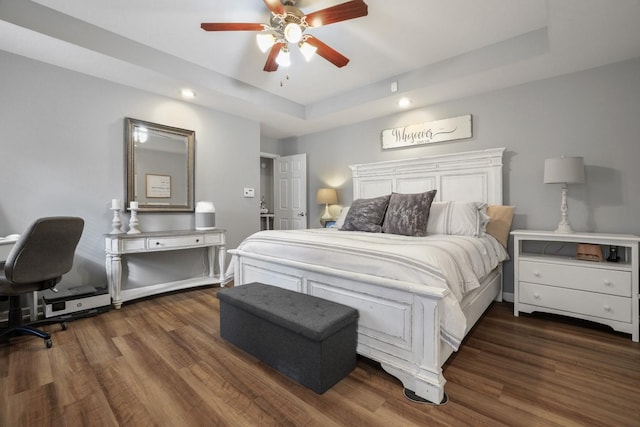 bedroom with ceiling fan, dark wood-type flooring, and a tray ceiling