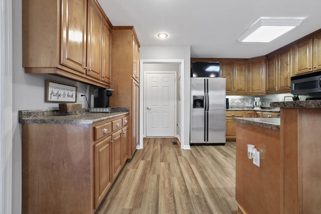 kitchen with stainless steel refrigerator with ice dispenser and light wood-type flooring