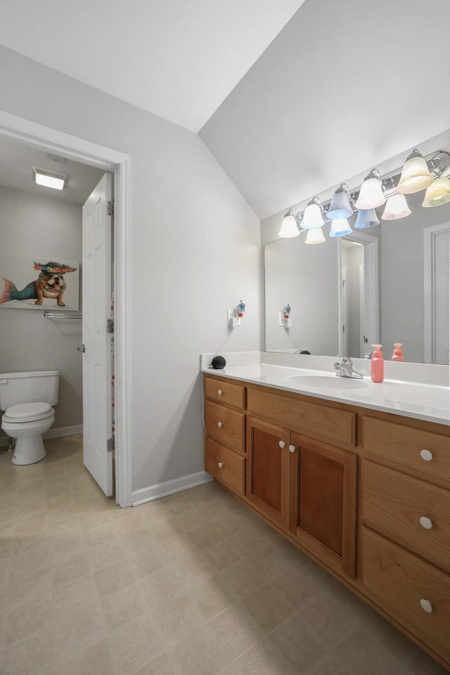 bathroom featuring toilet, lofted ceiling, and vanity