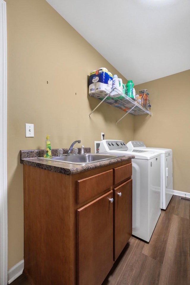 laundry room with washer and clothes dryer, dark hardwood / wood-style flooring, sink, and cabinets