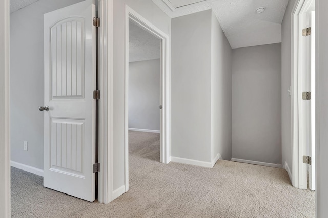 hallway featuring light carpet and a textured ceiling