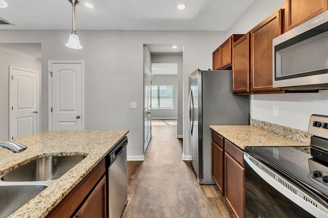 kitchen featuring dark hardwood / wood-style floors, pendant lighting, sink, light stone countertops, and appliances with stainless steel finishes