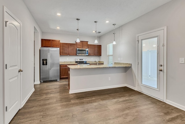 kitchen featuring kitchen peninsula, stainless steel appliances, dark hardwood / wood-style flooring, hanging light fixtures, and sink