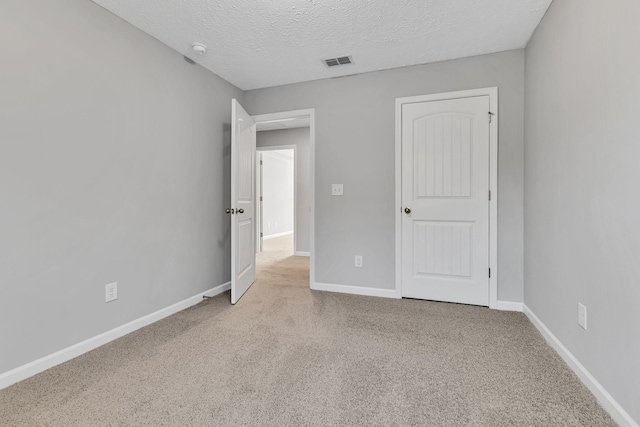 unfurnished bedroom featuring a textured ceiling and light carpet