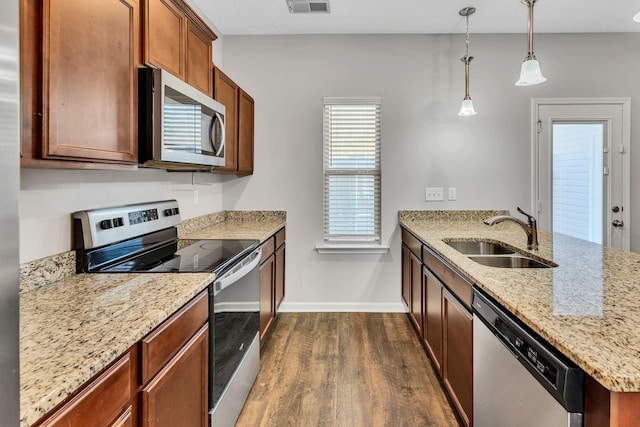 kitchen featuring decorative light fixtures, sink, light stone countertops, stainless steel appliances, and dark hardwood / wood-style flooring