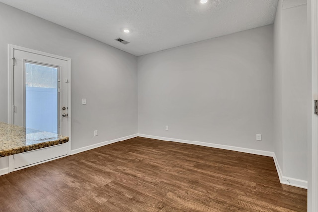 unfurnished room featuring a textured ceiling and dark hardwood / wood-style flooring