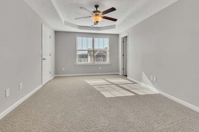 carpeted empty room featuring ceiling fan, a textured ceiling, and a raised ceiling