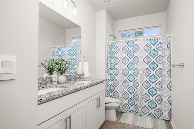 bathroom featuring toilet, vanity, tile patterned flooring, and walk in shower