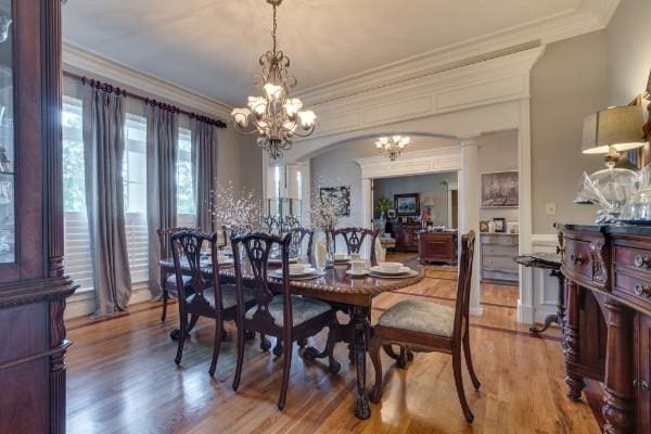 dining room with light wood-type flooring, a chandelier, and crown molding