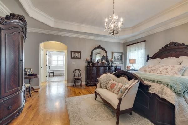 bedroom with ornamental molding, light hardwood / wood-style floors, a raised ceiling, and a chandelier