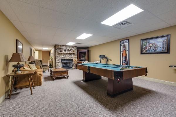 recreation room featuring pool table, a stone fireplace, and carpet flooring