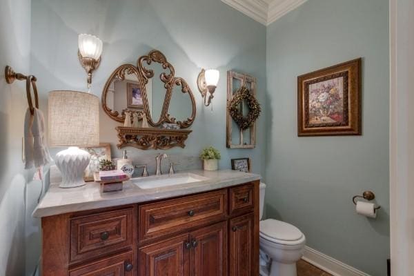 bathroom with toilet, ornamental molding, and vanity