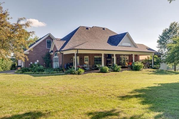 rear view of house featuring a lawn and covered porch