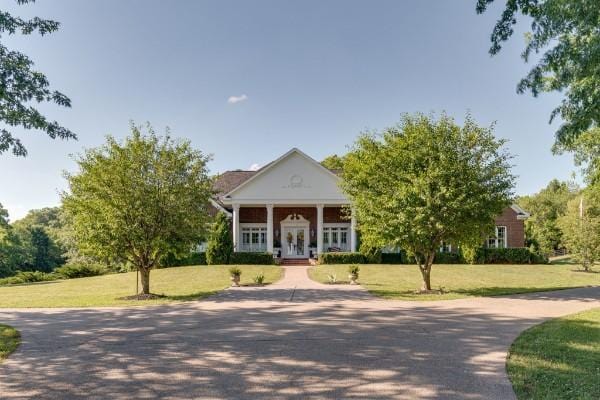 neoclassical / greek revival house featuring covered porch and a front yard