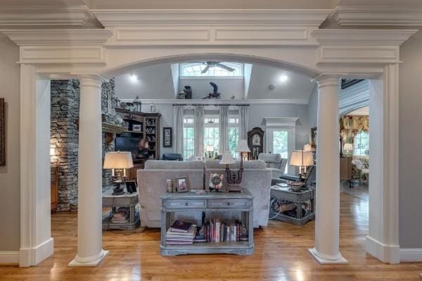 interior space featuring a wealth of natural light, wood-type flooring, ornamental molding, and ornate columns