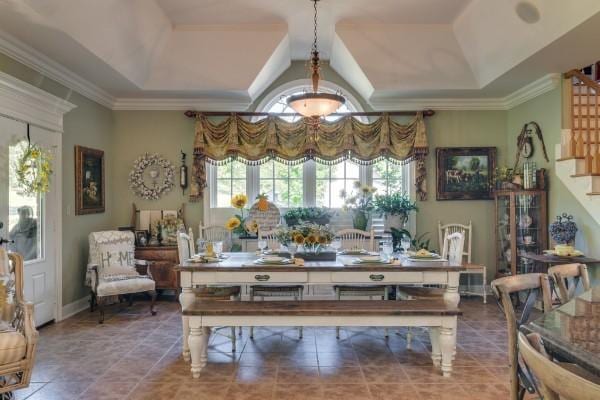 dining area with a tray ceiling and ornamental molding