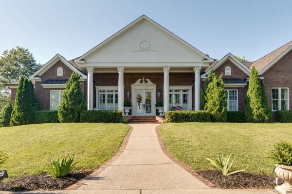 greek revival inspired property with a front lawn, french doors, and covered porch