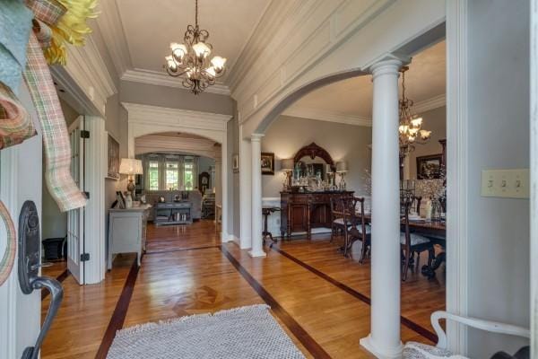 entryway featuring ornamental molding, a chandelier, and decorative columns