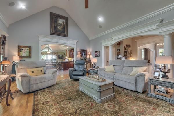 living room featuring hardwood / wood-style floors, ceiling fan, high vaulted ceiling, decorative columns, and crown molding