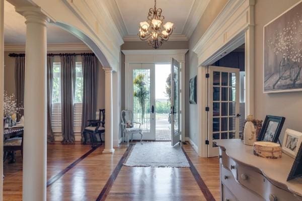 foyer entrance with light hardwood / wood-style flooring, plenty of natural light, and decorative columns