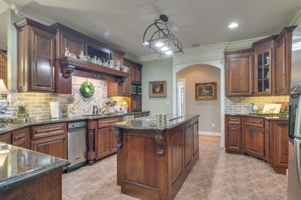 kitchen featuring tasteful backsplash, decorative light fixtures, a center island, sink, and ornamental molding