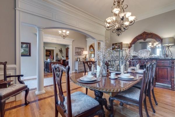 dining area with light wood-type flooring, ornamental molding, a chandelier, and ornate columns