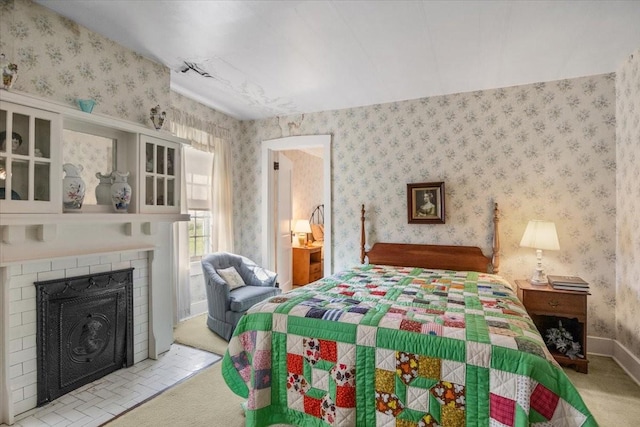 bedroom with light colored carpet and a fireplace