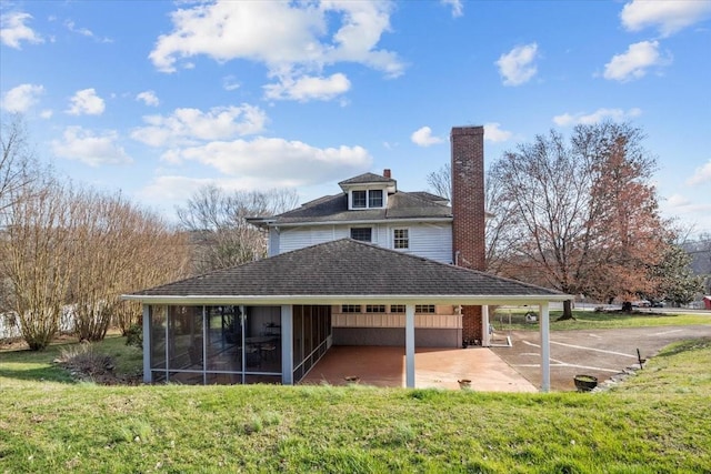 back of house with a patio area, a sunroom, and a lawn