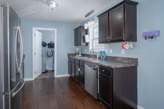 kitchen featuring sink, hanging light fixtures, dark brown cabinetry, stainless steel appliances, and a textured ceiling