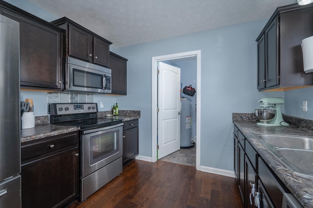 kitchen with dark wood-type flooring, water heater, dark brown cabinets, stainless steel appliances, and a textured ceiling