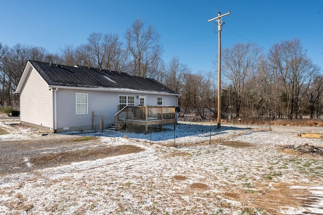 snow covered rear of property with a deck