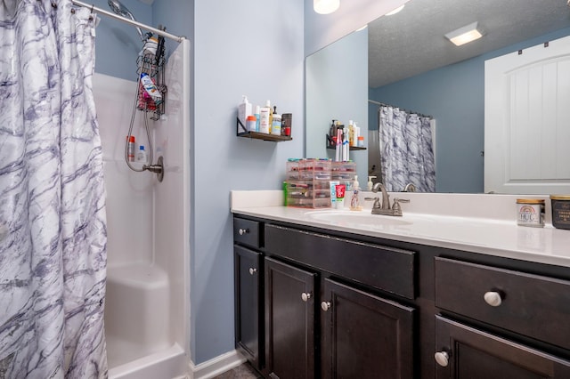 bathroom with walk in shower, vanity, and a textured ceiling