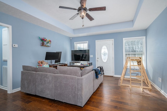 living room with ceiling fan, dark hardwood / wood-style floors, and a raised ceiling