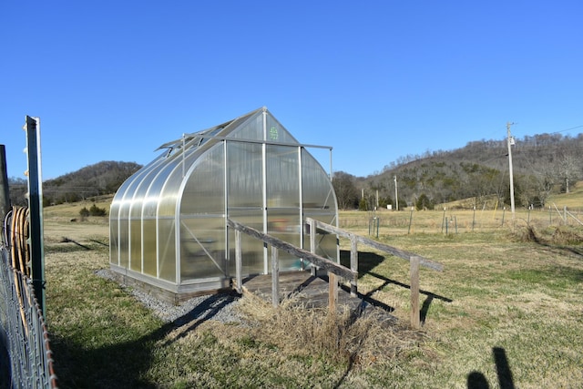 view of outbuilding with a mountain view, a lawn, and a rural view