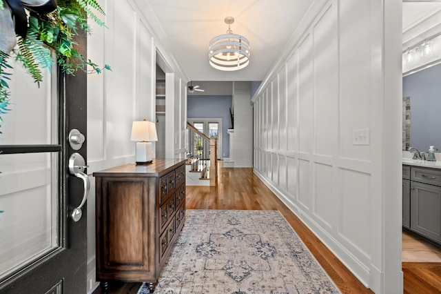 hallway with crown molding, light hardwood / wood-style flooring, and a chandelier