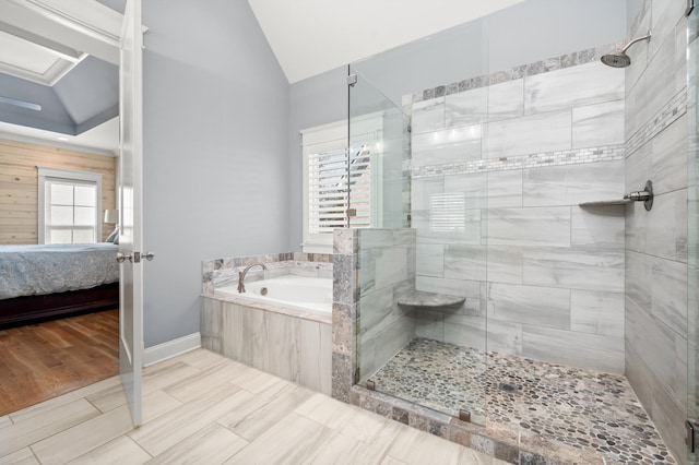 bathroom featuring independent shower and bath, vaulted ceiling, and a wealth of natural light