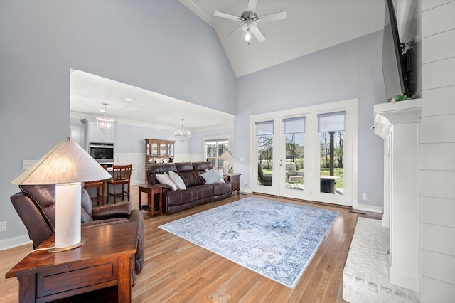 living room with ornamental molding, high vaulted ceiling, ceiling fan with notable chandelier, and light hardwood / wood-style floors