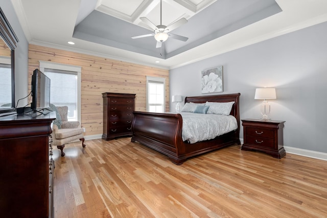 bedroom with wooden walls, ceiling fan, light hardwood / wood-style floors, a raised ceiling, and crown molding